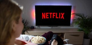 Person watching Netflix on a TV while holding a bowl of popcorn