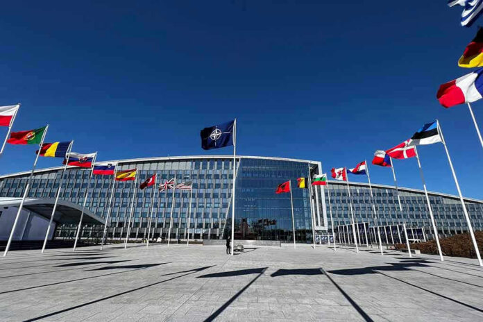 2284120437 Flags outside NATO headquarters building under clear blue sky.