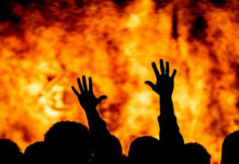 Silhouetted hands raised against a fiery background.