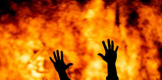 Silhouetted hands raised against a fiery background.