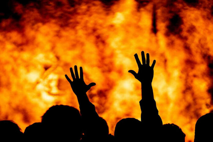1746475793 Silhouetted hands raised against a fiery background.