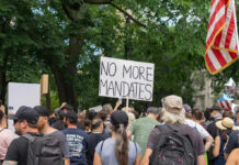 Billionaire Baby Factory Exposes Citizenship Loophole Crowd holds No More Mandates sign at protest.