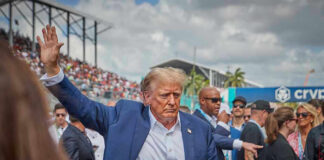 Secret Service Meltdown Exposed Person in blue suit waving at outdoor event.