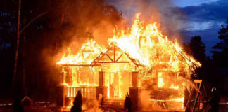 Holiday Fun Turns Homicide House engulfed in flames with firefighters present.