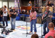 A band performing live on stage with an audience in front