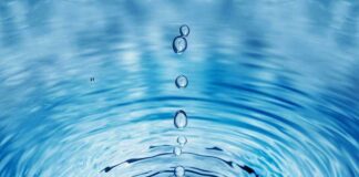 Close-up of water droplets creating ripples in a blue water surface