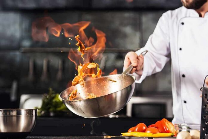 Chef tossing food in a flaming pan