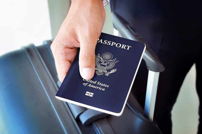 A person holding a United States passport next to a suitcase
