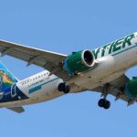 Airliner with green engines flying against a clear blue sky