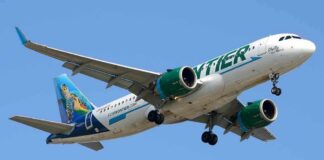 Airliner with green engines flying against a clear blue sky
