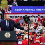 Speaker at podium addressing large crowd at political rally