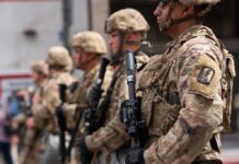 DOJ Torches D.C. Council Over National Guard Demand Soldiers in camouflage gear stand in formation holding rifles