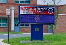 Electronic school marquee in front of a brick high school