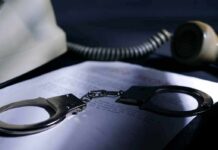 Handcuffs on a document beside a coiled telephone handset