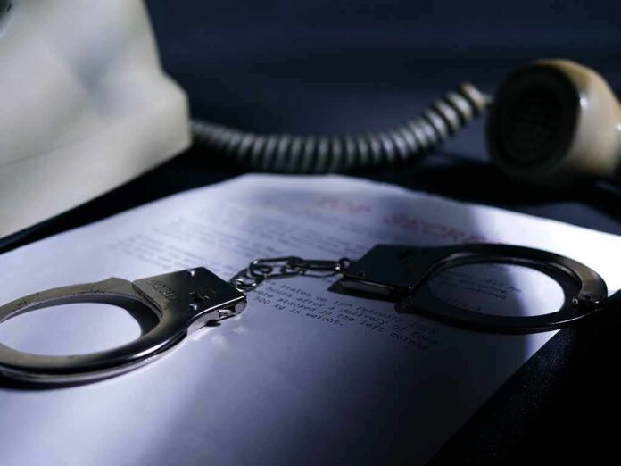 Handcuffs on a document beside a coiled telephone handset