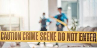 crime scene tape in a living room with two officers in background