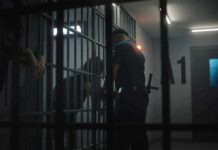 police officer at a jail cell with detainees behind bars