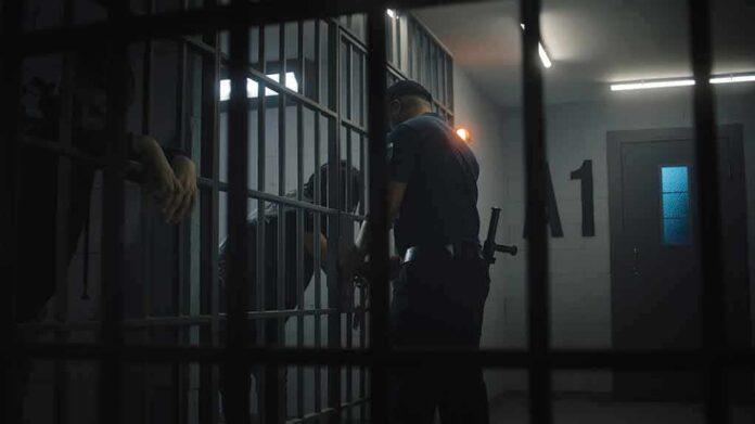 police officer at a jail cell with detainees behind bars