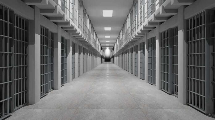 Prison corridor lined with barred cells on both sides