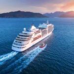 Cruise ship sailing at sunset near mountainous coast