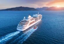 Cruise ship sailing at sunset near mountainous coast