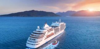 Cruise ship sailing at sunset near mountainous coast
