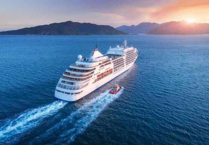 shutterstock_1011917770 Cruise ship sailing at sunset near mountainous coast