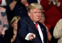 Trump Threatens to SUE Soros, Google, Apple and More man in suit pointing toward the camera at an event