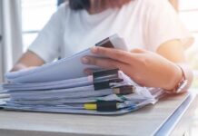NYC’s SECRET 9/11 Air Files Finally Released Person organizing a stack of documents with binder clips