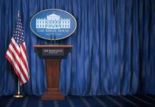 Why The WHPress Corps Should Stop Whining About Access and Start Reporting White House press briefing podium with U.S. flag and blue curtain