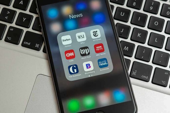 Smartphone displaying a folder of news apps on a laptop keyboard