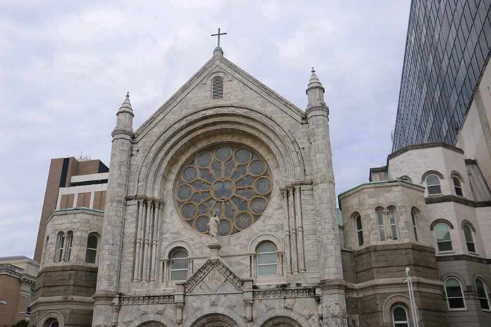 shutterstock_1659149962 Stone church facade with large rose window and cross