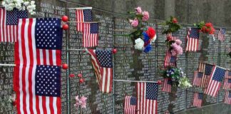 9/11 Gatekeepers Target The Mayor Memorial wall adorned with American flags and flowers