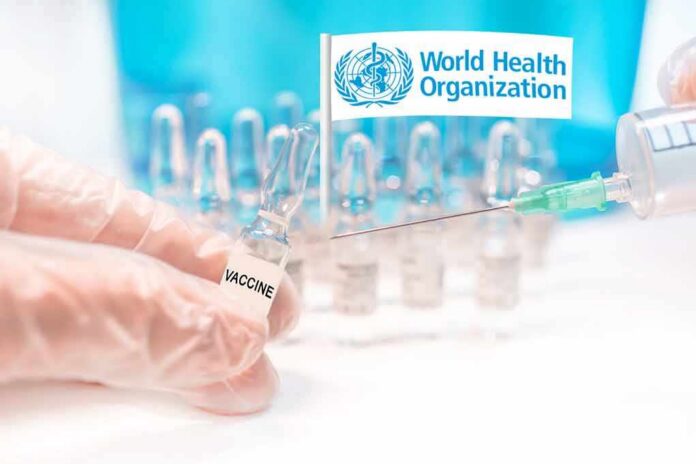 shutterstock_1864835041 Gloved hands holding vaccine vial and syringe near WHO banner