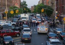 Police vehicles and officers block a city street during an active scene
