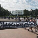 Protesters hold a reparations banner outside the White House