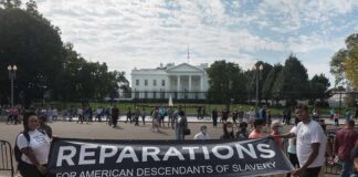 Protesters hold a reparations banner outside the White House