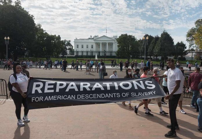 Protesters hold a reparations banner outside the White House