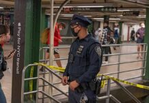 Police officer stands in a subway station near caution tape