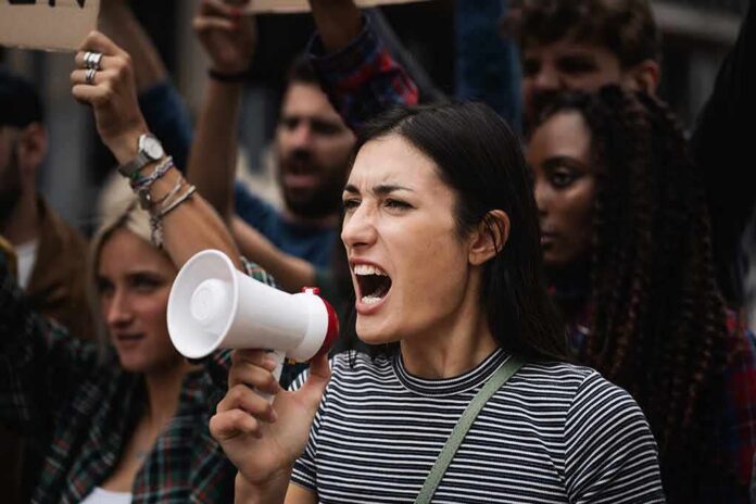 shutterstock_2107619402 Woman with megaphone shouting at a protest