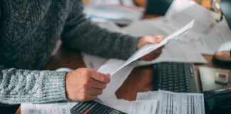 The AI Bubble Just POPPED And They’re Coming For Your 401(k) Person reviewing bills with calculator at cluttered desk