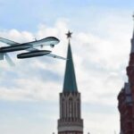 military drone flying near ornate red-brick towers