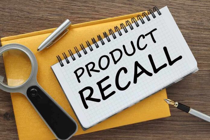 Notebook with product recall note beside magnifying glass and pen