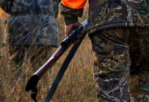 Cops Find Headless Animal Stuffed in Trash Bags Hunter in camouflage holding a rifle in tall grass