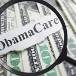 Magnifying glass over cash highlighting Obamacare text