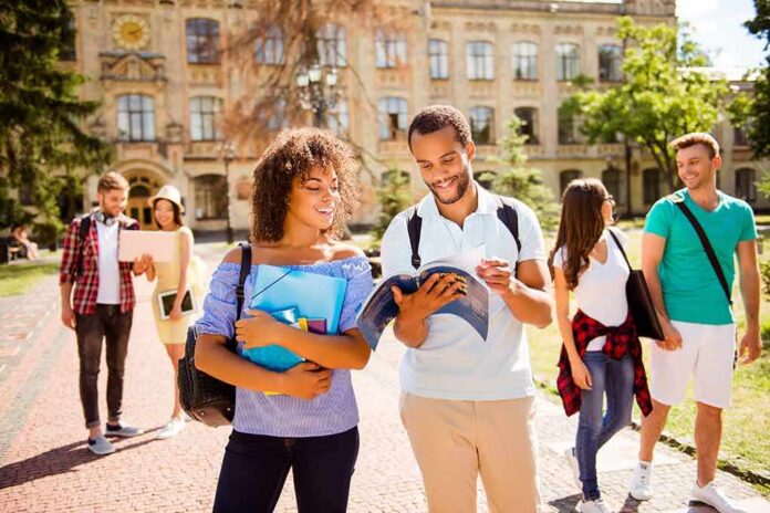 shutterstock_684325948 College students walking on campus with books and backpacks