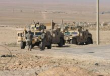 Soldiers near armored vehicles in a desert