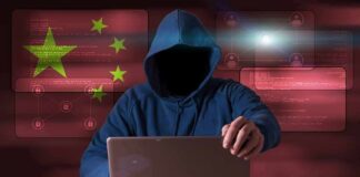Hooded figure using a laptop with red cybersecurity graphics