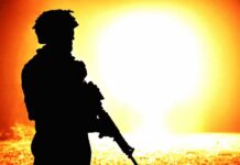 silhouette of an armed soldier against a bright fiery background
