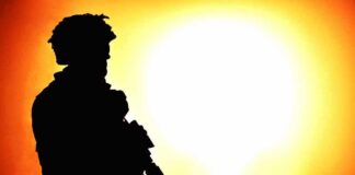 silhouette of an armed soldier against a bright fiery background